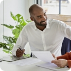 Man wearing business attire smiles while talking with his client.